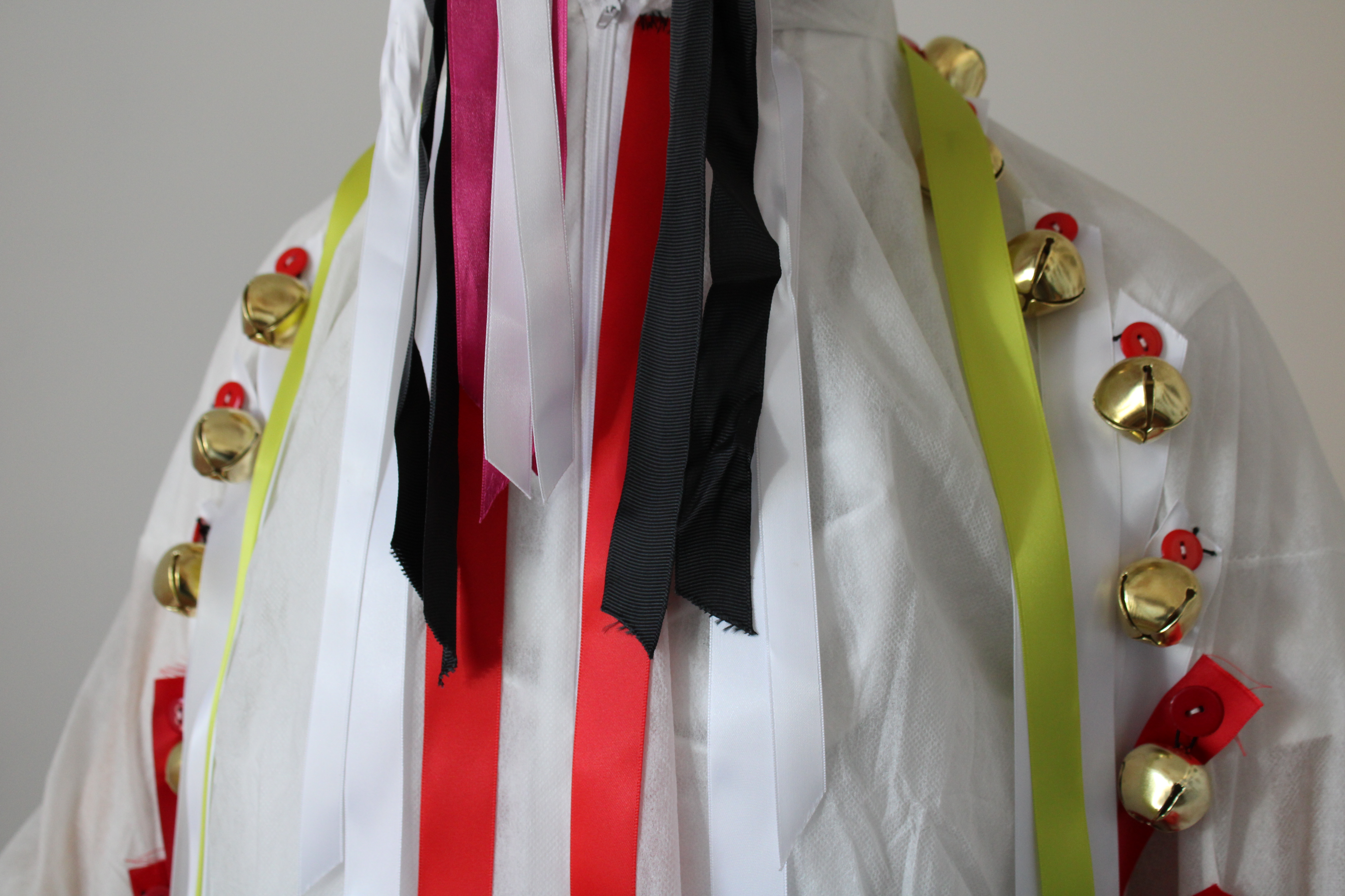 Upper torso in white costume with bells and ribbons