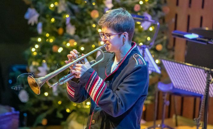 Laura Jurd playing trumpet in front of a lit Christmas tree
